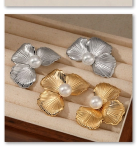 Detailed view of silver and gold stainless steel pearl flower earrings on a tray