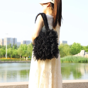 Outdoor shot of a black tiered tulle shoulder bag with ruffled layers and 3D floral texture