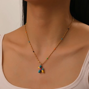 Detail of colorful enamel balloon dog pendant on a beaded gold chain worn by a model