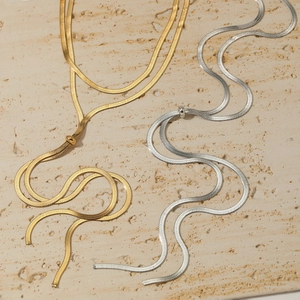 Collier maille serpent plate en or et argent sur fond de pierre naturelle beige