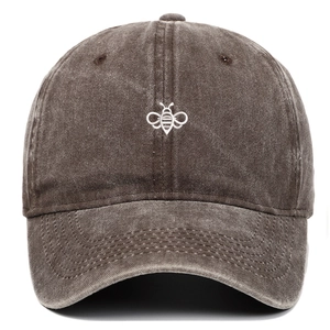 Close-up of white bee embroidery on vintage washed cotton baseball cap in dark brown