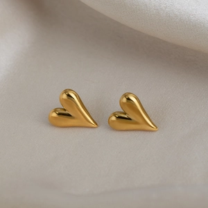 Detail of 18K gold-plated stainless steel heart studs on soft beige silk background