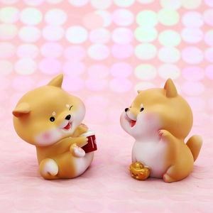 Close-up of cute resin Shiba Inu figurines with lucky gold ingot and red cup ornaments