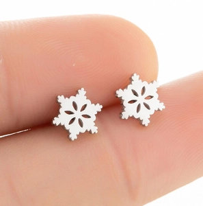 Macro shot of silver hollow snowflake stud earrings held by hand for size reference