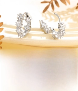 Macro shot of silver star-shaped zircon huggie earrings with a 10mm inner diameter
