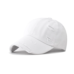 Detailed close-up of distressed white cotton baseball cap with vintage frayed hole design