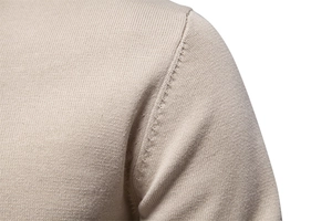 Gros plan sur la couture de l'épaule d'un pull en maille fine beige pour homme