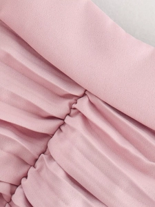 Macro shot of light pink dress pleated fabric showing high-density texture and silk feel