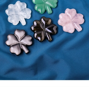 Detailed view of five multi-colored crystal four-leaf clovers on blue silk fabric