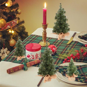 Set of four 30cm mini tabletop Christmas trees with burlap base on a festive dinner table