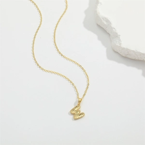 Gold minimalist necklace featuring a letter E pendant with honeycomb texture pattern