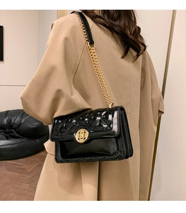 Detailed close-up of a black quilted leather shoulder bag featuring a gold floral metal clasp