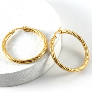 Elegant gold-plated twisted hoop earrings with a textured spiral design on a stone base