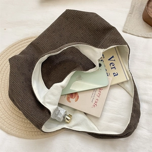 Vue de dessus du sac cabas en velours côtelé marron avec doublure en toile et accessoires