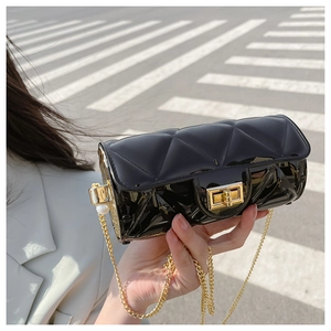Detail of black glossy quilted cylinder bag with gold chain and large pearl accent