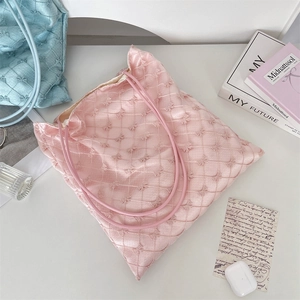 Detailed shot of pink quilted tote bag with bow embroidery and soft satin texture