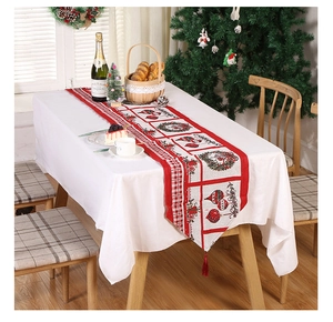 Close-up of festive red Christmas table runner with wreath patterns and red tassels
