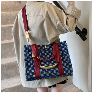 Detail of denim tote bag with blue checkered floral edge and red fabric shoulder strap