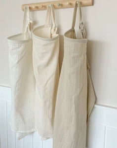 Detail of soft muslin cotton nursing covers in earth tones hanging on wooden hooks