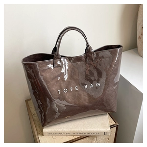 Detail of a brown glossy minimalist tote bag with TOTE BAG print on textured fabric