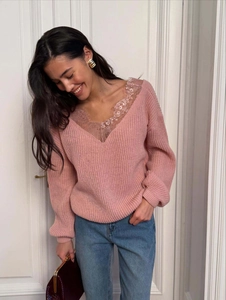 Close-up of pink knit sweater with delicate lace trim on the V-neckline and ribbed texture