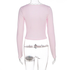 Back view of pink cropped long sleeve top with white lace trim on the neckline