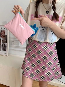 Pink canvas makeup bag with green zipper and woven label held by a hand