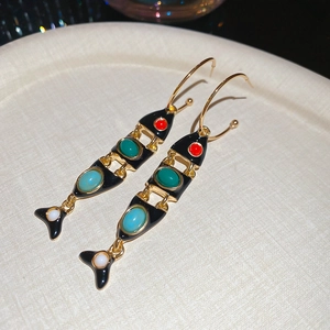 Detail view of gold fish-shaped tassel earrings with colorful stones and black enamel