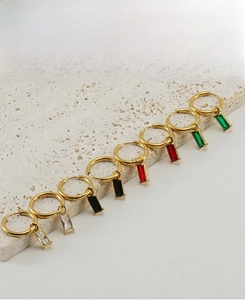 Detail van gouden roestvrijstalen oorringen met rechthoekige zirkoon hangers in vier kleuren