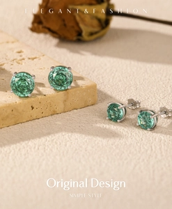 Elegant rose-cut green gemstone earrings in silver setting on aesthetic stone backdrop