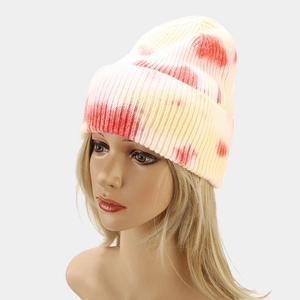 Close-up of a female model wearing a tie-dye orange and yellow knit beanie hat