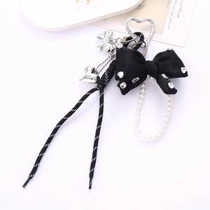 Close-up of stylish rhinestone bow charm with white pearls and woven nylon lanyard
