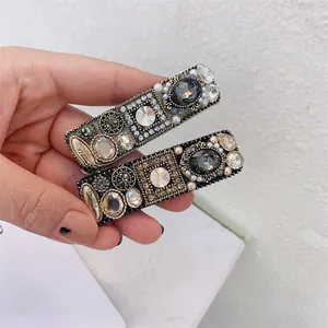 Detail of vintage BB clips with sparkling Czech rhinestones and pearls held in hand