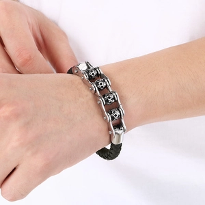 Punk silver stainless steel skull bracelet with black woven strap on a male wrist