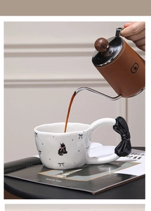 Detailed view of coffee being poured into a ceramic cat mug with a 3D bow handle