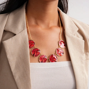 Detail of red enamel round pendants with gold chain worn on neck for a vintage jewelry look