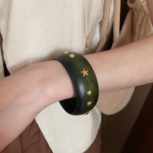 Détail du bracelet en bois vintage avec résine vert dégradé et rivets étoiles dorées