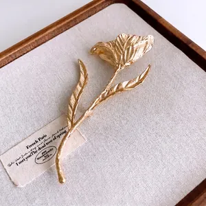 Elegant gold tulip brooch with hammered texture on a vintage tray with linen fabric