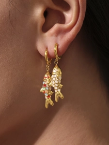 Close-up of elegant gold koi fish earrings with colorful enamel on a model's ear