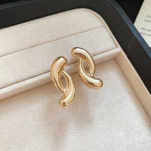 Detailed close-up of 18K gold knot stud earrings with a high-polished metallic finish