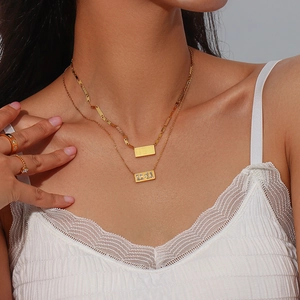 Close-up of a layered gold stainless steel necklace featuring a 11:11 rectangular pendant