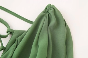 Détails macro d'une robe en tulle vert montrant les bretelles plissées et le tissu froncé
