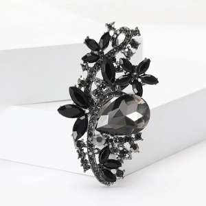 Macro detail of alloy flower brooch with pear-shaped grey crystal and black rhinestones