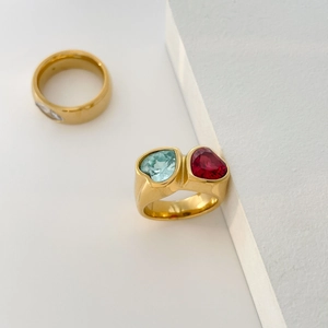 Close-up of gold titanium ring featuring light blue and red heart-shaped zircon stones