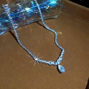 Close-up of elegant pear-cut zircon pendant on shimmering tennis chain with luxury detail