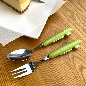 Detail of green cartoon crocodile handles on stainless steel spoon and fork set