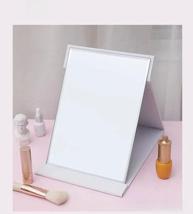Close-up of a white foldable vanity mirror with textured PU leather cover and makeup items