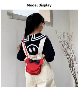 Detail showing red PU leather child crossbody bag with black bow and round ears