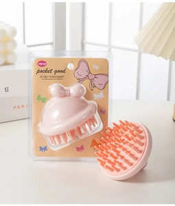 Pink silicone scalp massager with cute bow design and durable plastic handle detail