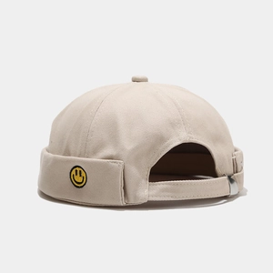 Detail of khaki cotton miki hat featuring yellow smiley face embroidery and metal strap